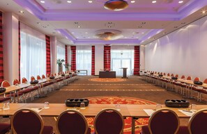 Una sala de conferencias con una mesa larga, sillas y un atril.