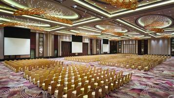 A large conference room with rows of chairs, a patterned carpet, and modern ceiling design.