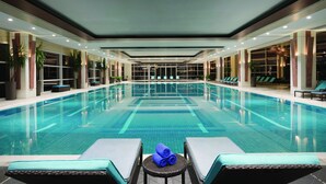Ein Hallenbad mit Liegestühlen und einem Tisch mit Handtüchern.