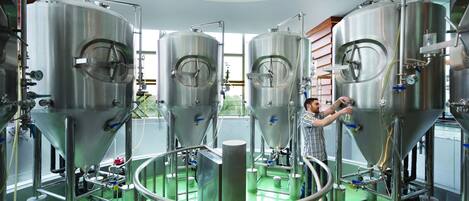 A modern industrial setting with stainless steel tanks and a green floor, likely a brewery or distillery.
