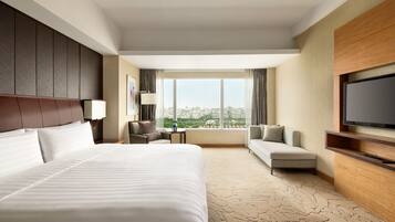Une chambre d’hôtel avec un grand lit, un canapé, une télévision et une vue sur la ville.