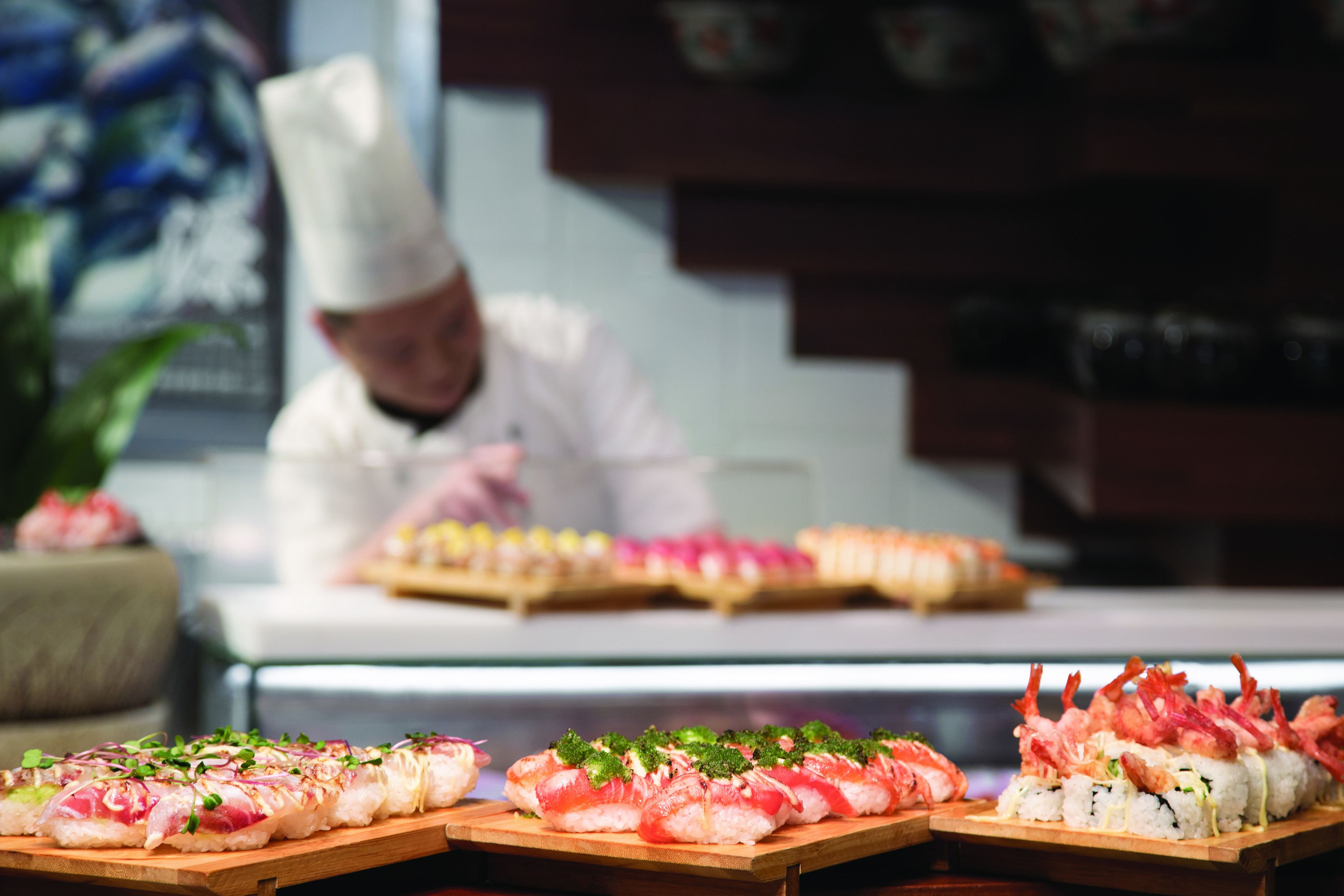 A sushi display with various types of sushi on wooden boards.
