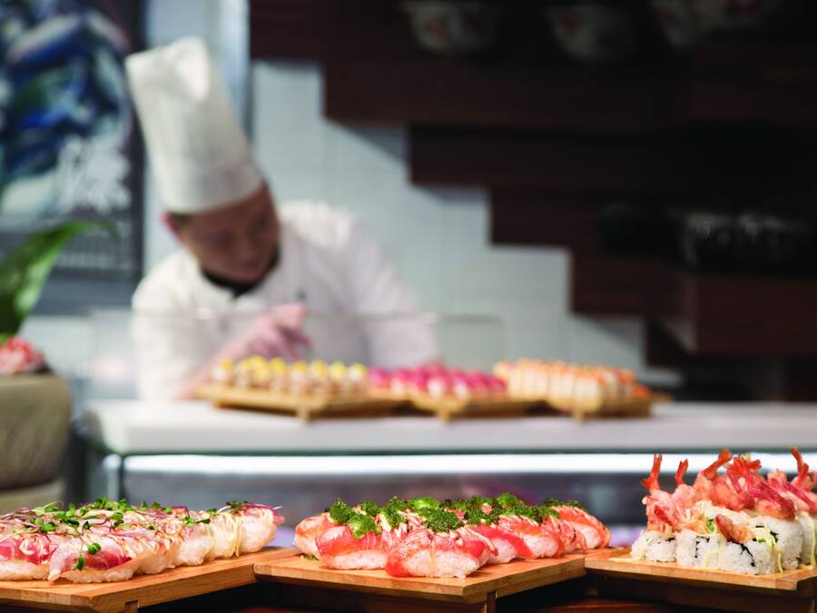 Een sushi-presentatie met verschillende soorten sushi op houten planken.