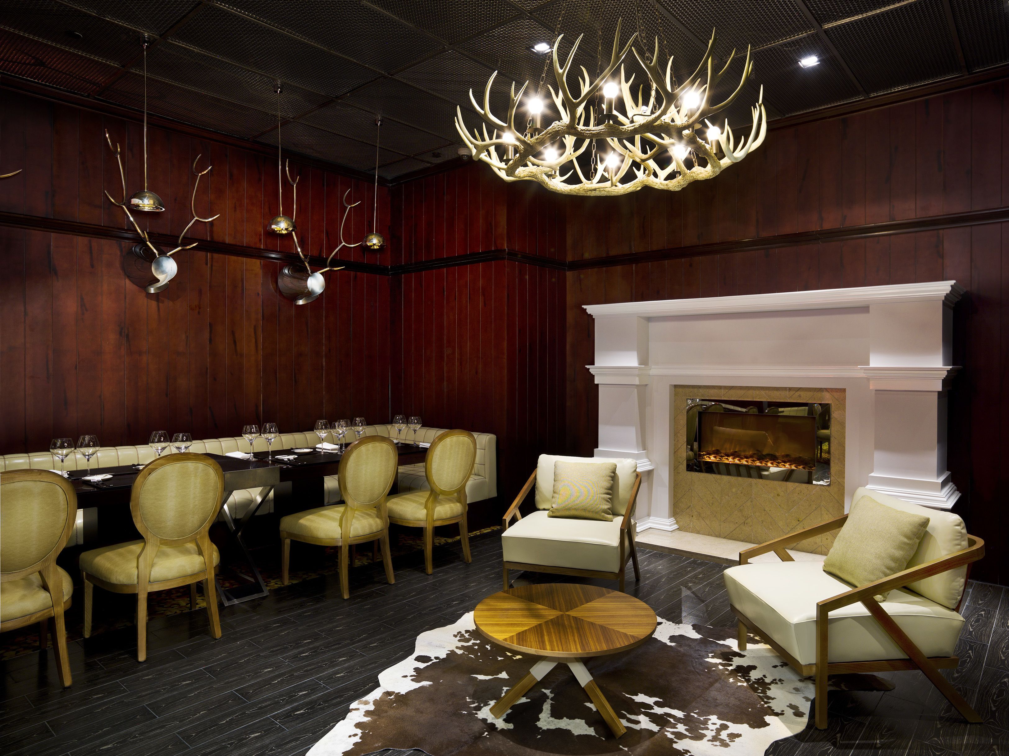 A dining area with a long table set for a meal, surrounded by chairs, a fireplace, and a chandelier.