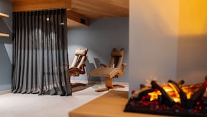 A modern living room with a fireplace, two wooden chairs, and a large window with curtains. - Relax Hotel Restaurant Pip Margraff (Sankt-Vith)