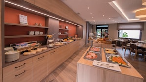 A modern hotel dining area with buffet-style food service, wooden cabinetry, and a clean, contemporary design. - Relax Hotel Restaurant Pip Margraff (Sankt-Vith)