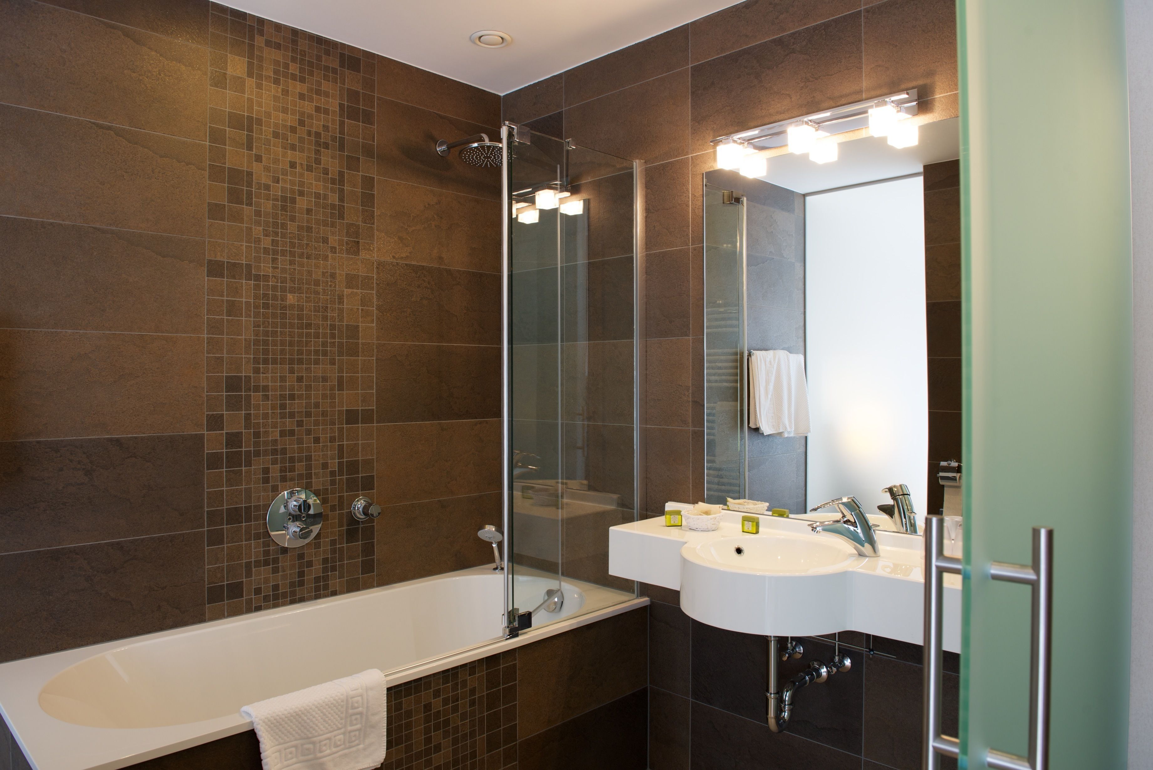 Une salle de bain moderne avec une douche à parois de verre, une baignoire blanche et deux lavabos avec miroirs.