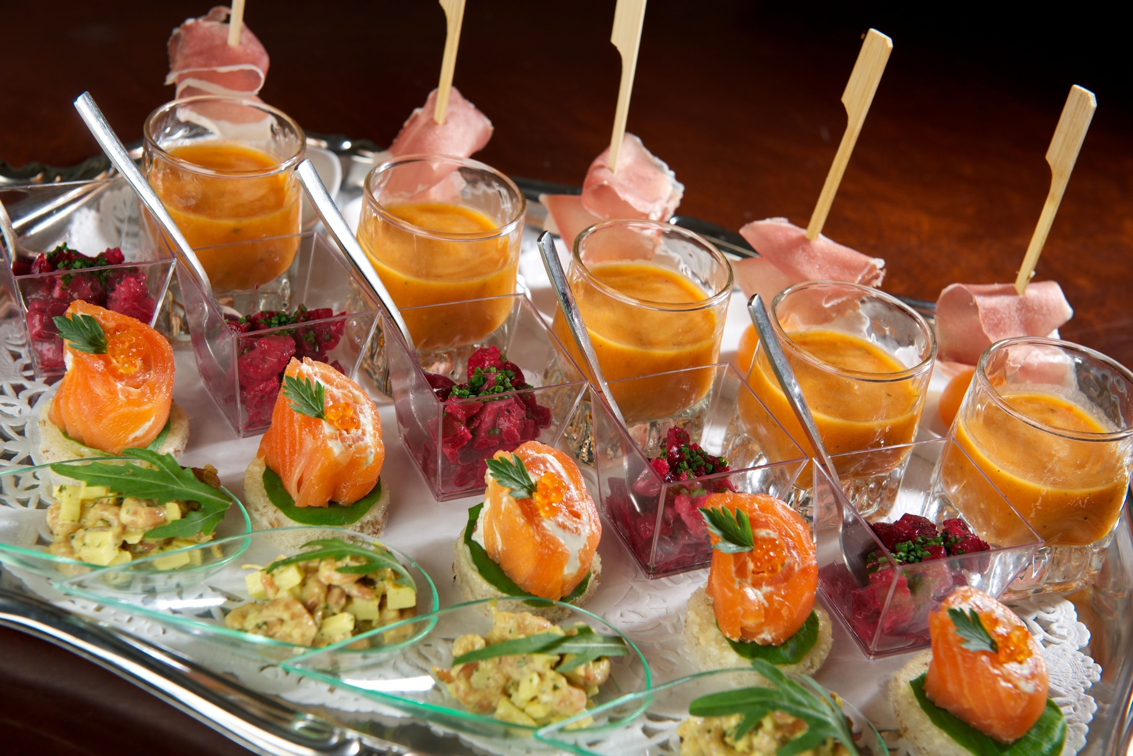 Una bandeja de aperitivos variados, con salmón, fruta y diferentes preparaciones.