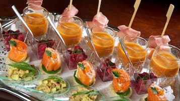 Una bandeja de aperitivos variados, con salmón, fruta y diferentes preparaciones.