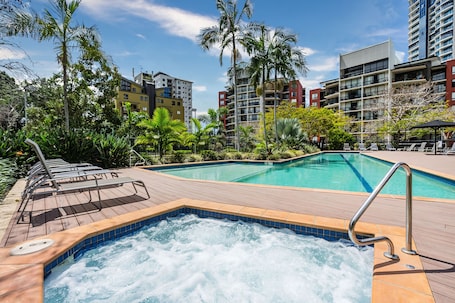Una piscina al aire libre, sillones reclinables de piscina