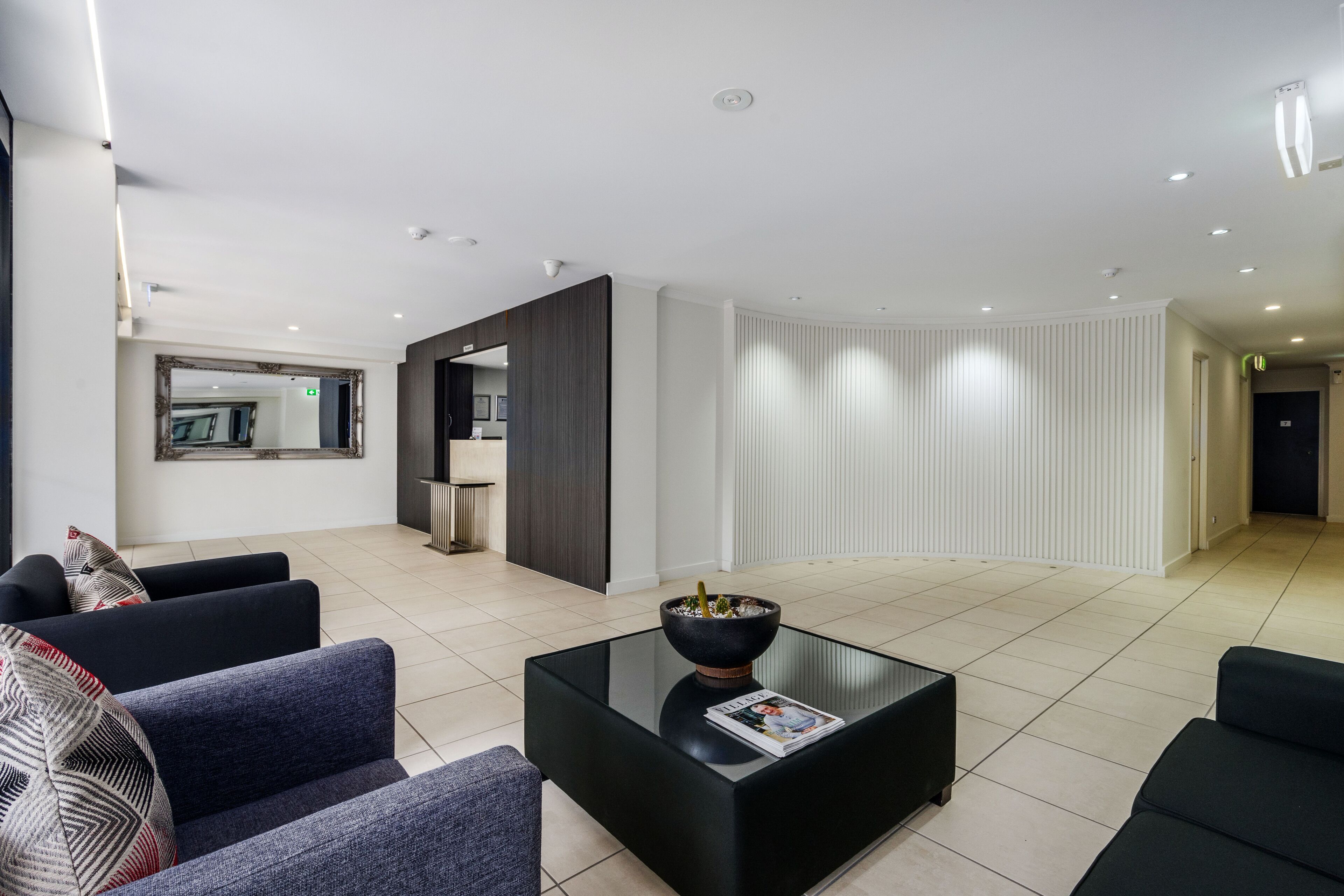 A modern living room with a black coffee table, a sofa, and a dining area with a kitchen in the background.
