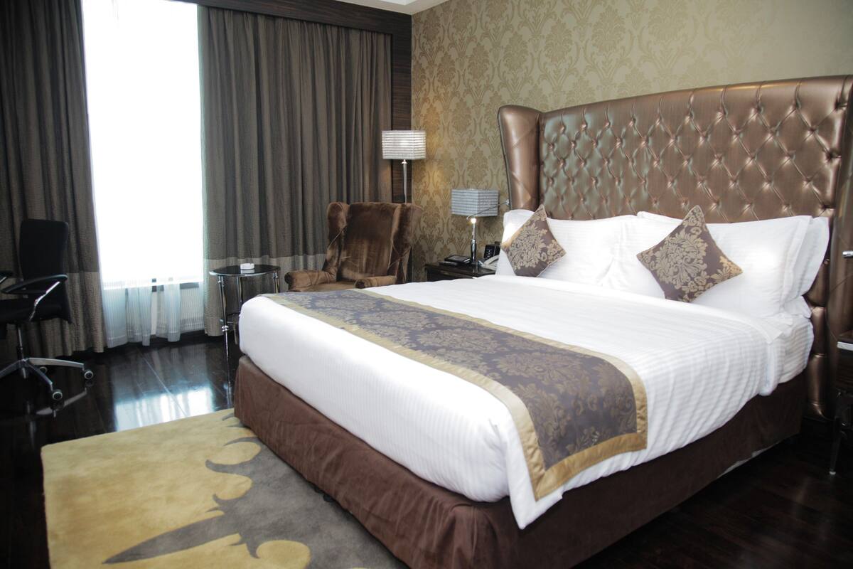 Une chambre d’hôtel avec un grand lit, une chaise, un bureau et une lampe.