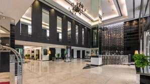A spacious lobby with a high ceiling, large windows, and a modern chandelier.