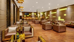 A spacious lobby with leather sofas, a bar area, and a large screen.