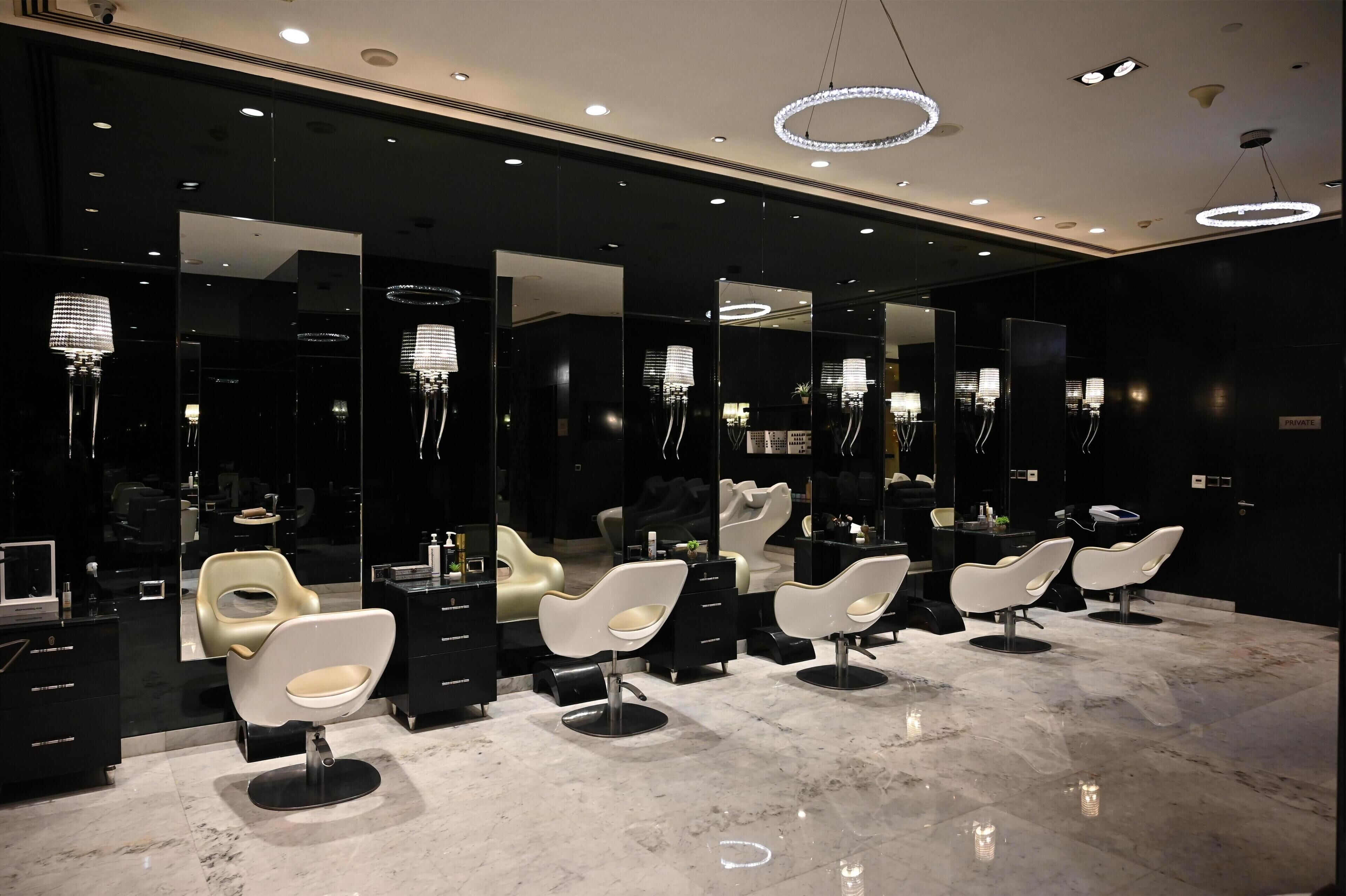 Un salón moderno con múltiples espejos, sillas blancas y suelo de mármol.