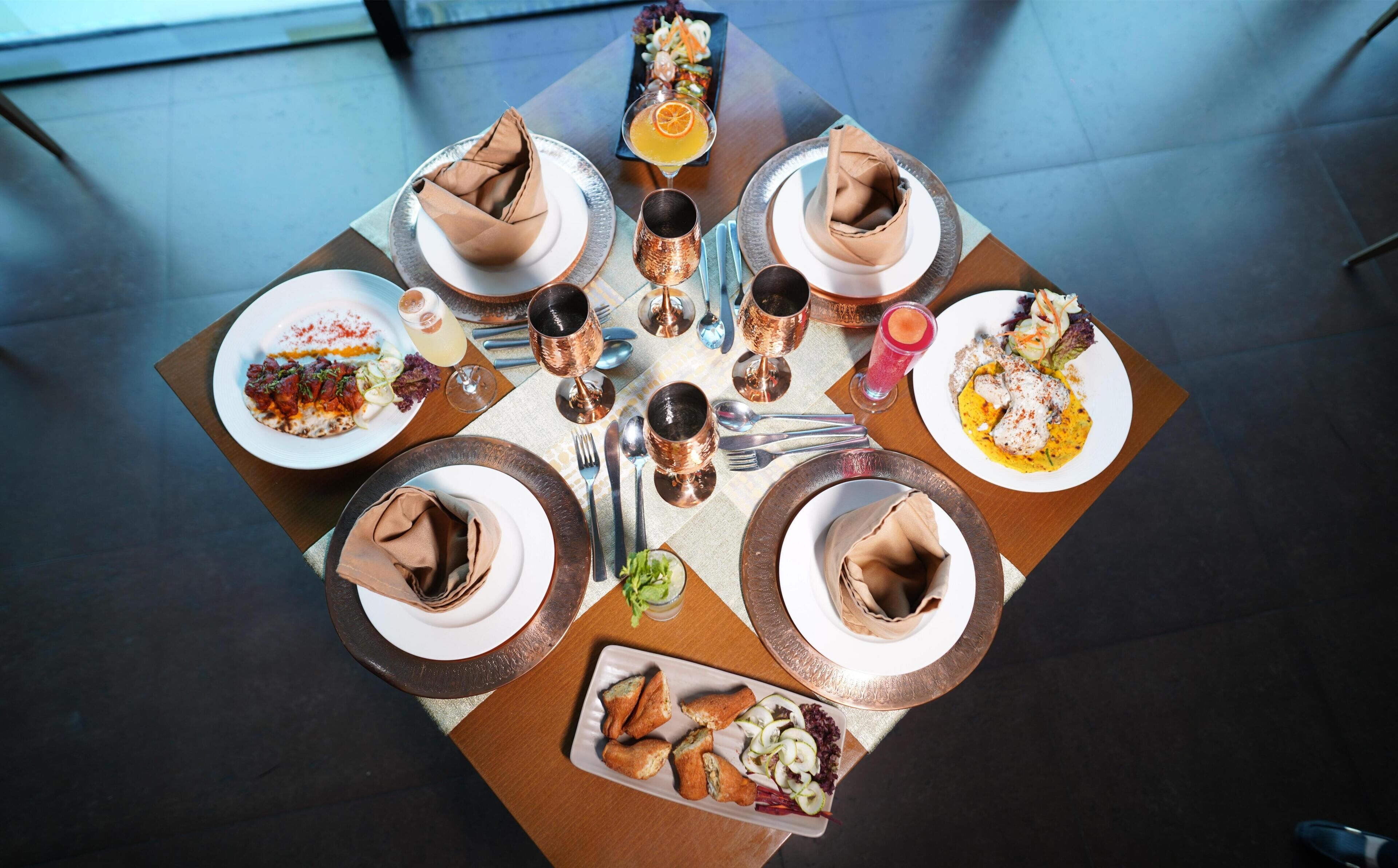 A dining table with multiple plates of food, glasses, and cutlery.