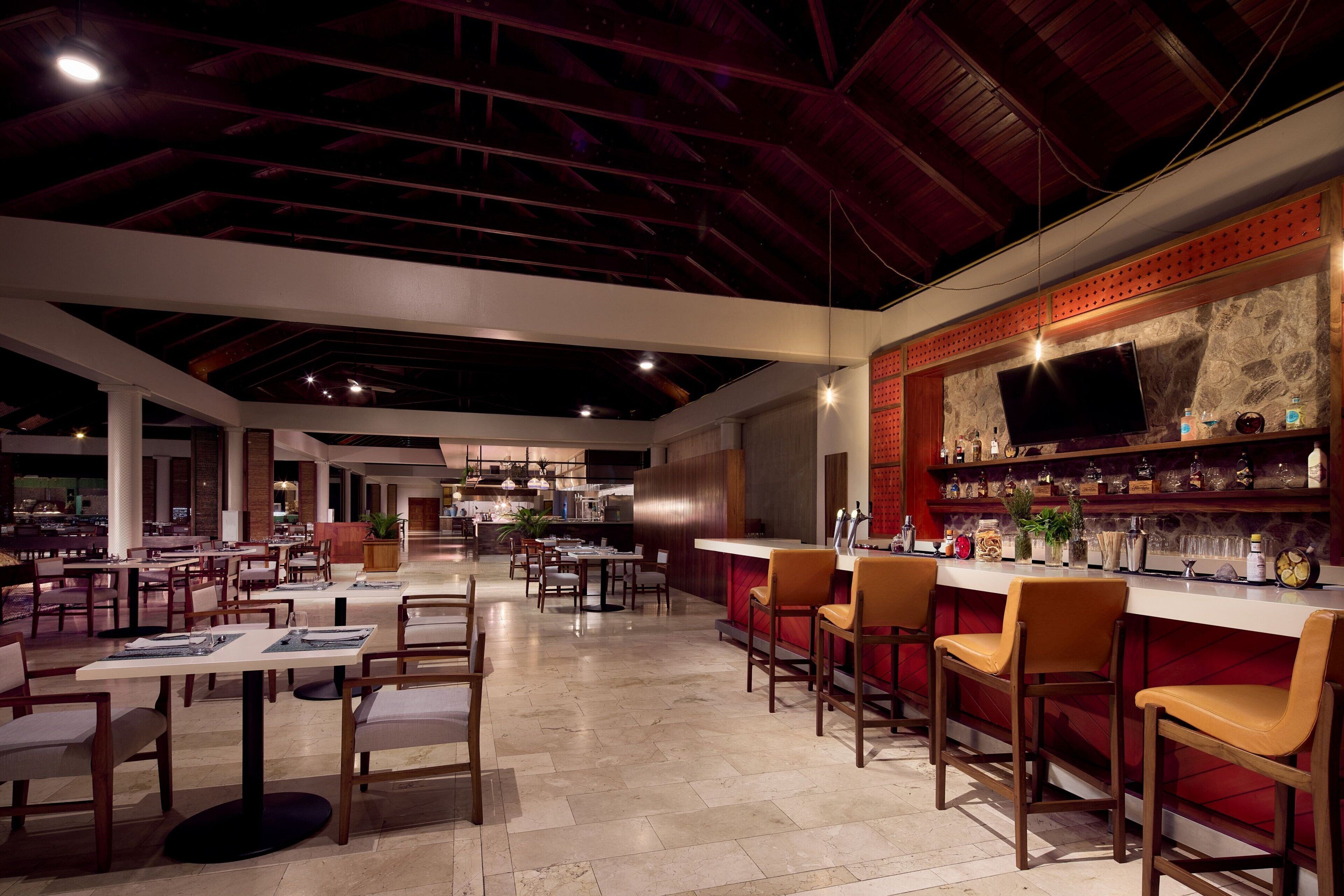 A spacious restaurant with high ceilings, a bar area, and multiple seating arrangements.