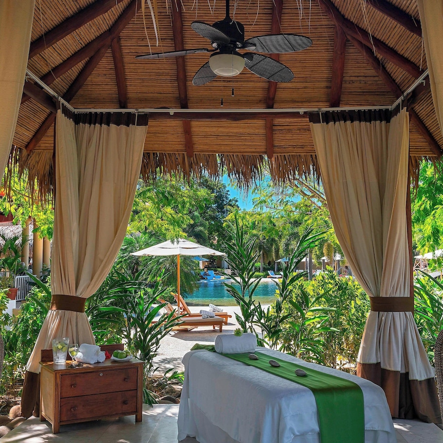 A room with a bed, a nightstand, a large vase, and a ceiling fan.
