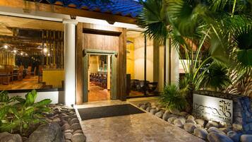 Entrada a un restaurante con un camino de piedra, una puerta de madera y un letrero que dice 'Bamboo Asian Blend Restaurant'.