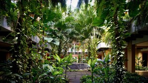 A lush indoor garden with a stone pathway leading to a central area, surrounded by dense foliage and plants.