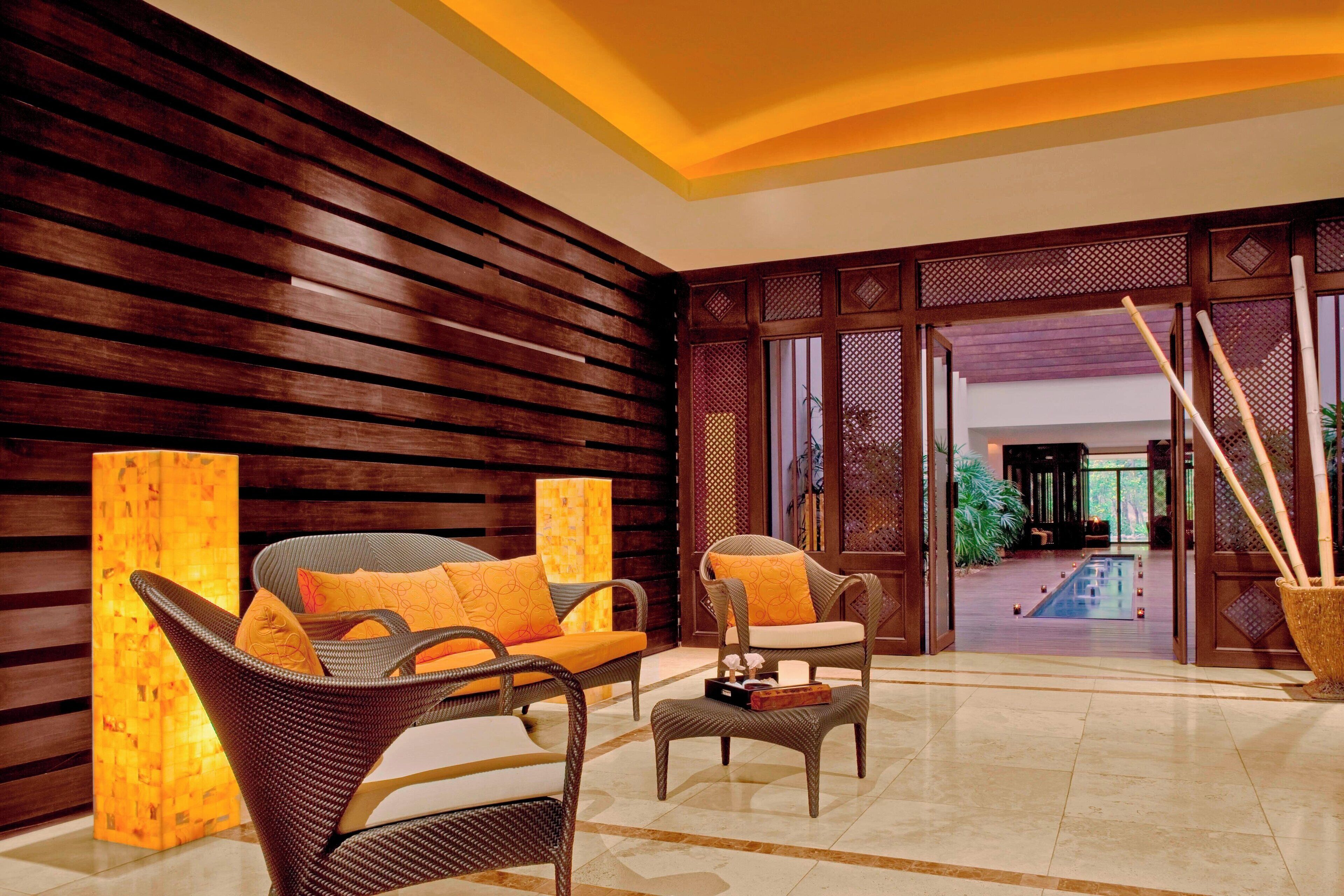 A lobby with wicker furniture, a large pillar, and a view of a pool area.