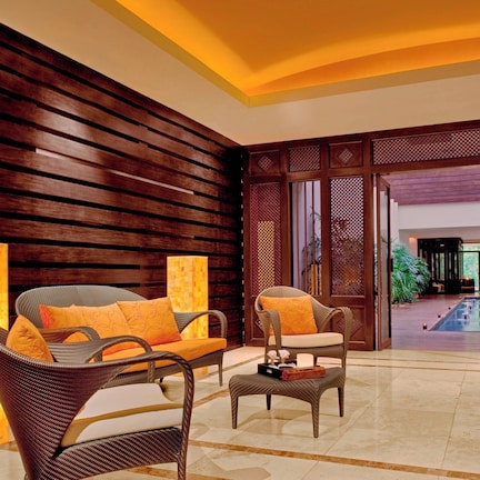 A lobby with wicker furniture, a large pillar, and a view of a pool area.