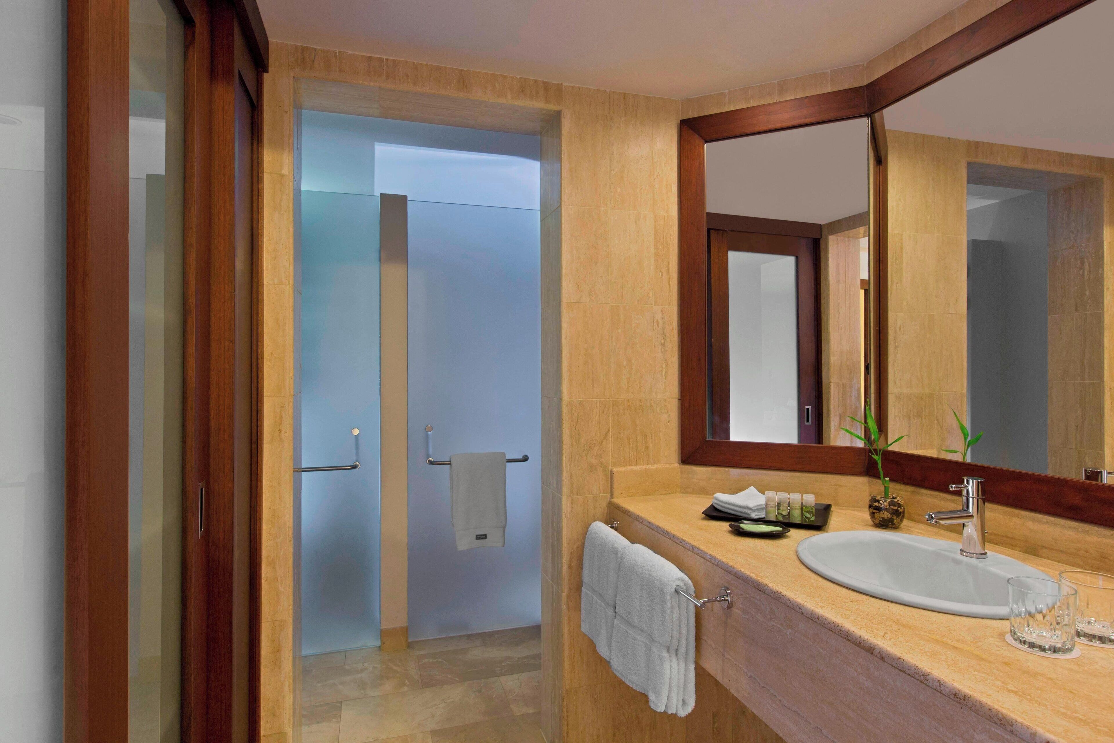 A modern bathroom with a large mirror, a sink, and a shower area.