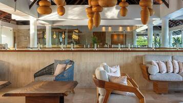 A modern lobby with a wooden reception desk, wicker chairs, and a sofa with cushions.