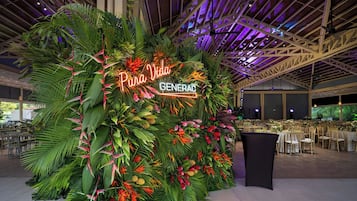 A reception area with a large plant wall, a neon sign, and a seating area with tables and chairs.