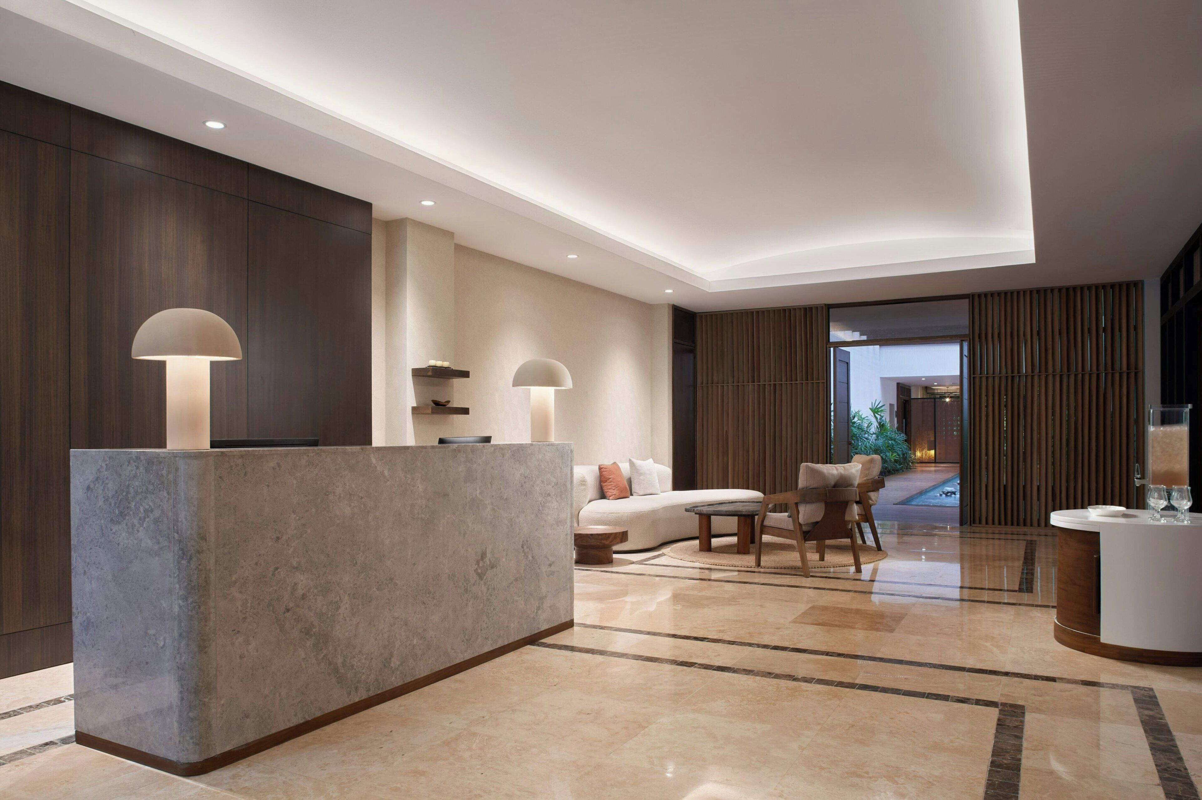 A modern lobby with a reception desk, seating area, and a view of the outdoors.