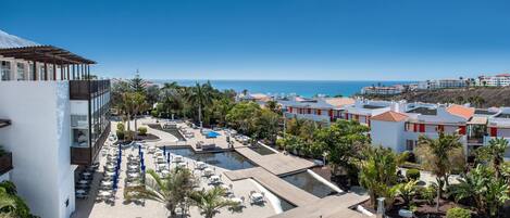 A resort with a pool area, outdoor seating, and views of the ocean.