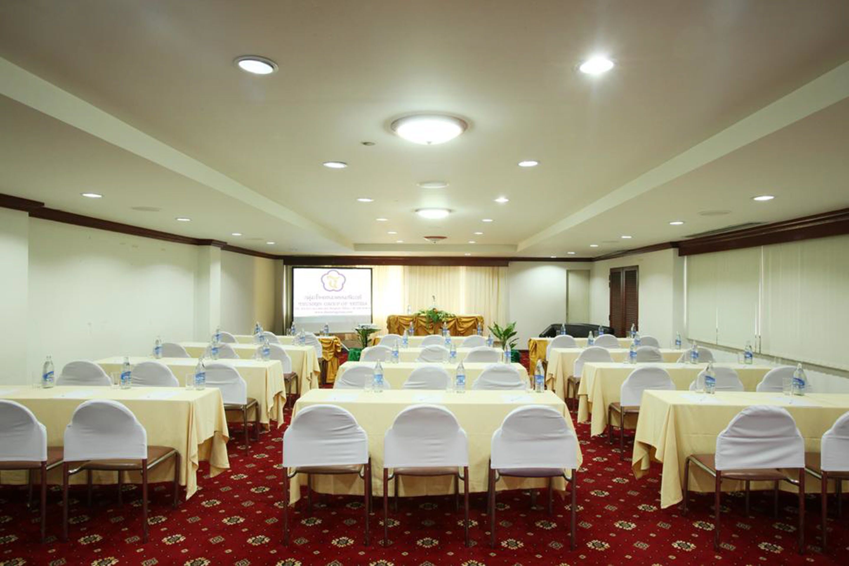 Uma sala de conferência com mesas, cadeiras dispostas em fileiras e um pódio.