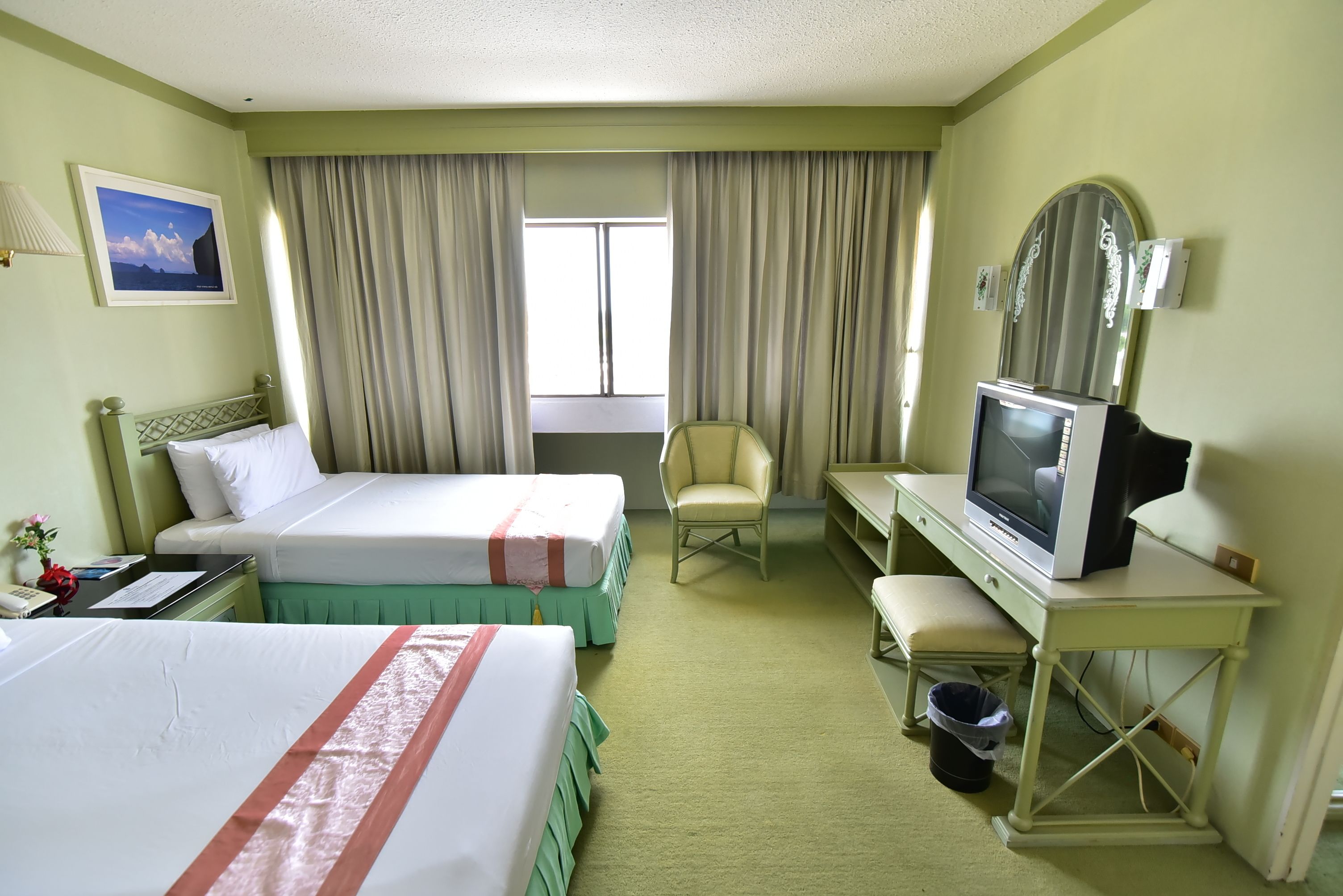 Una habitación de hotel con dos camas, televisión, escritorio y una silla.