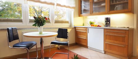 Una cocina moderna con comedor, que incluye una mesa redonda, dos sillas y un frutero.