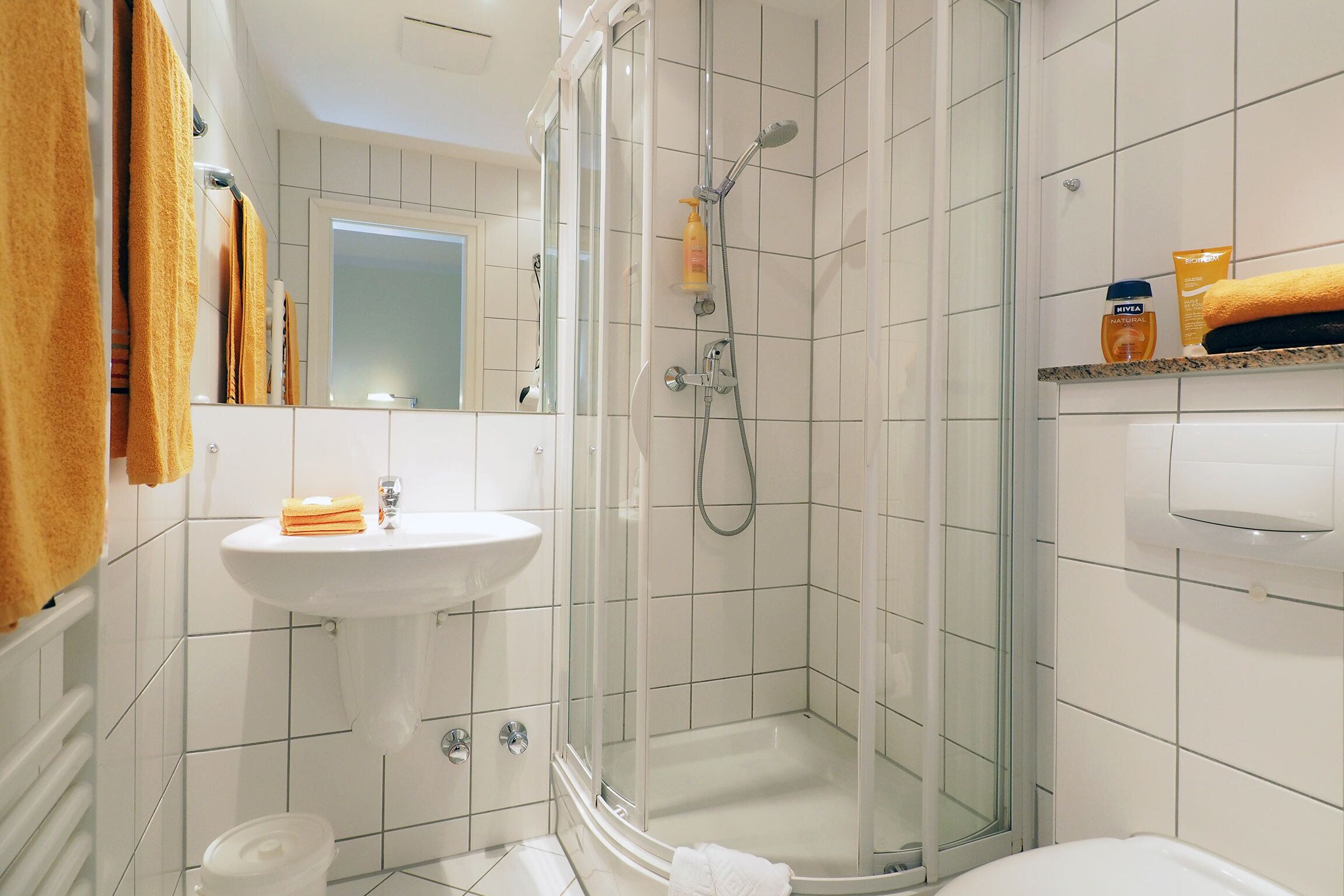 A modern bathroom with a glass-enclosed shower, a white sink, and a mirror.