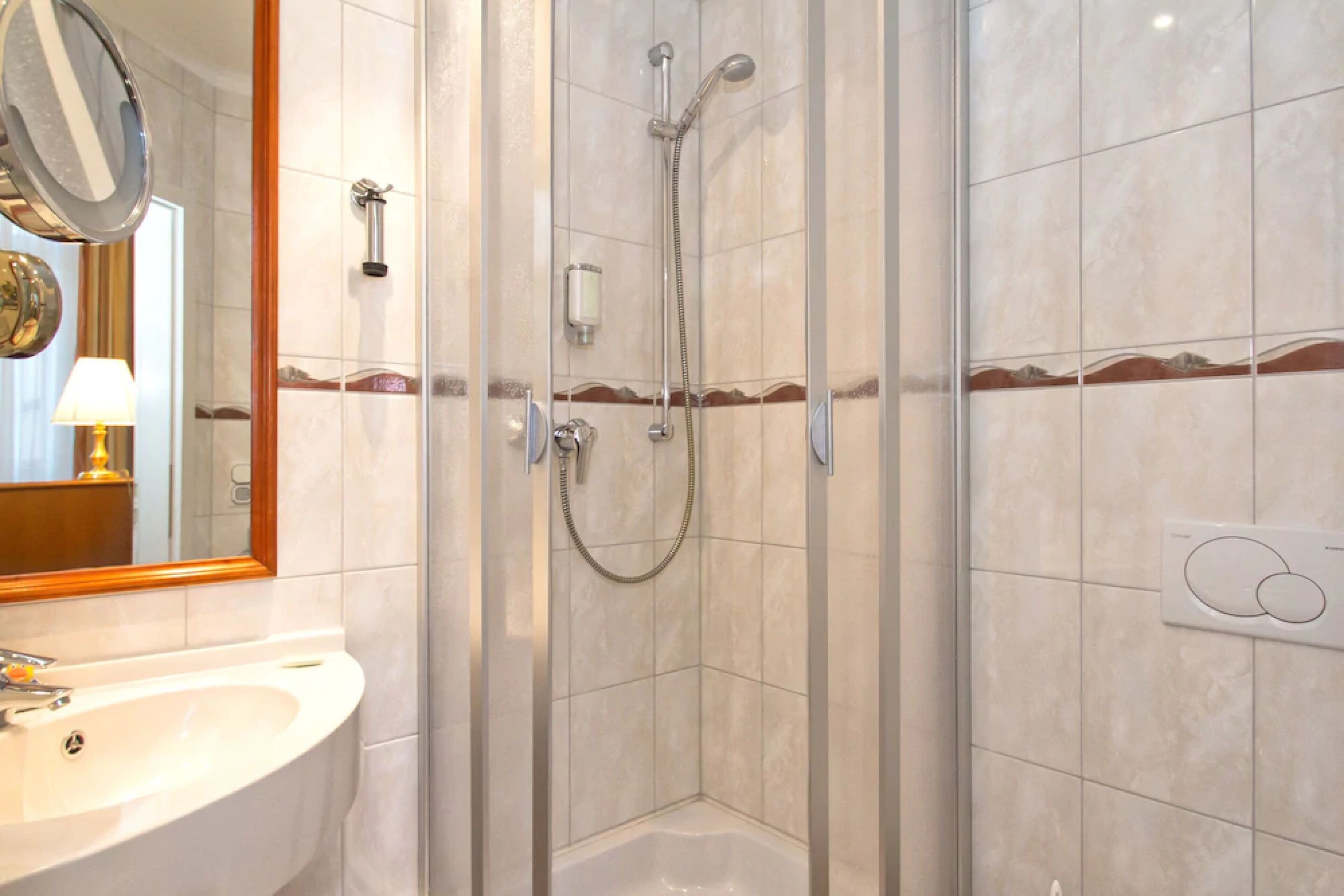 Ein Badezimmer mit einer Duschkabine, einem Waschbecken und einem Spiegel.