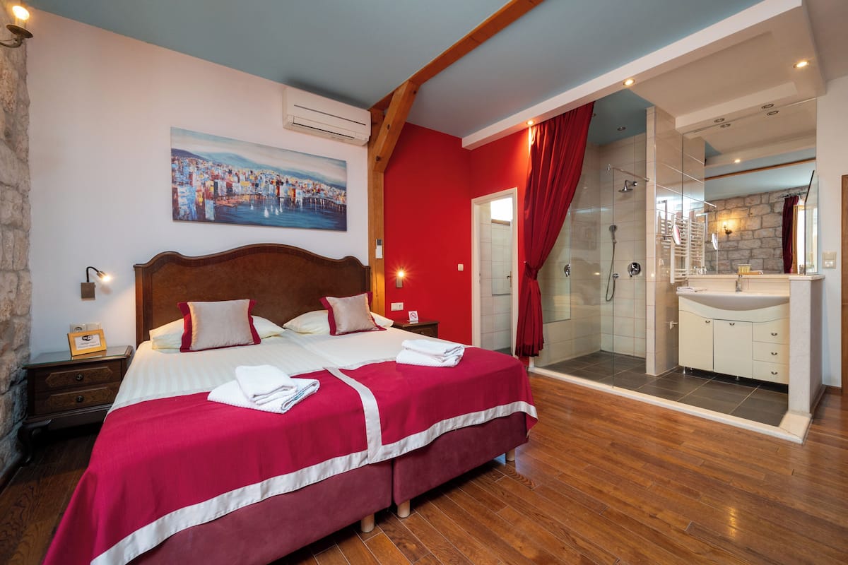 A hotel room with a bed, a shower area, and a bathroom with a sink.