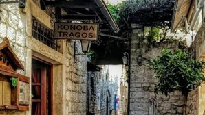 Una calle adoquinada estrecha con edificios de piedra, una puerta de madera y barriles.