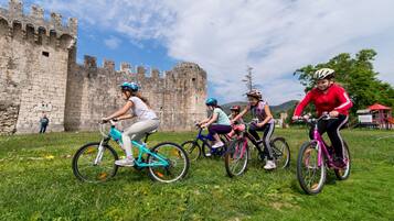 Un grupo de personas montando bicicletas sobre un campo cubierto de césped, con un castillo al fondo.
