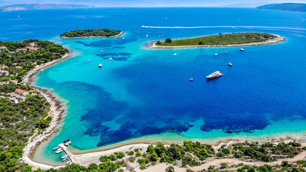 Vista aérea de una zona costera con aguas azul cristalino, barcos y pequeñas islas.