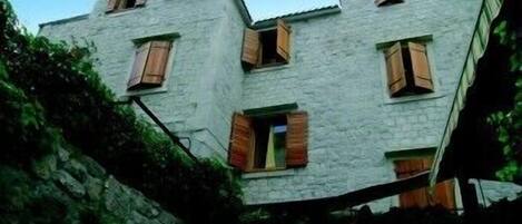 A two-story building with stone walls and wooden shutters on the windows.