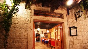 Pasillo de paredes de piedra que conduce a un comedor con muebles de madera y luces colgantes.