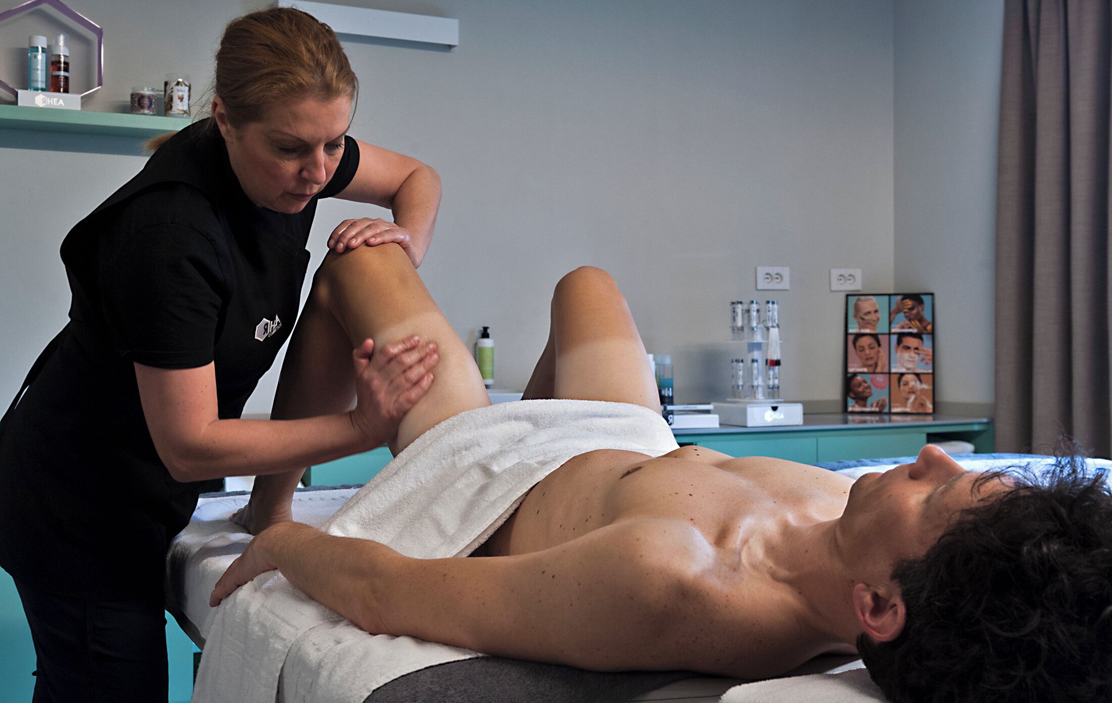 A massage therapy session in a room with a massage table, a towel, and a shelf with various items.