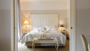 A hotel room with a bed, bedside tables, a tray table with breakfast items, and slippers on the floor.
