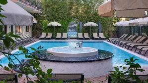 Een zwembadgedeelte met ligbedden, een jacuzzi en parasols.