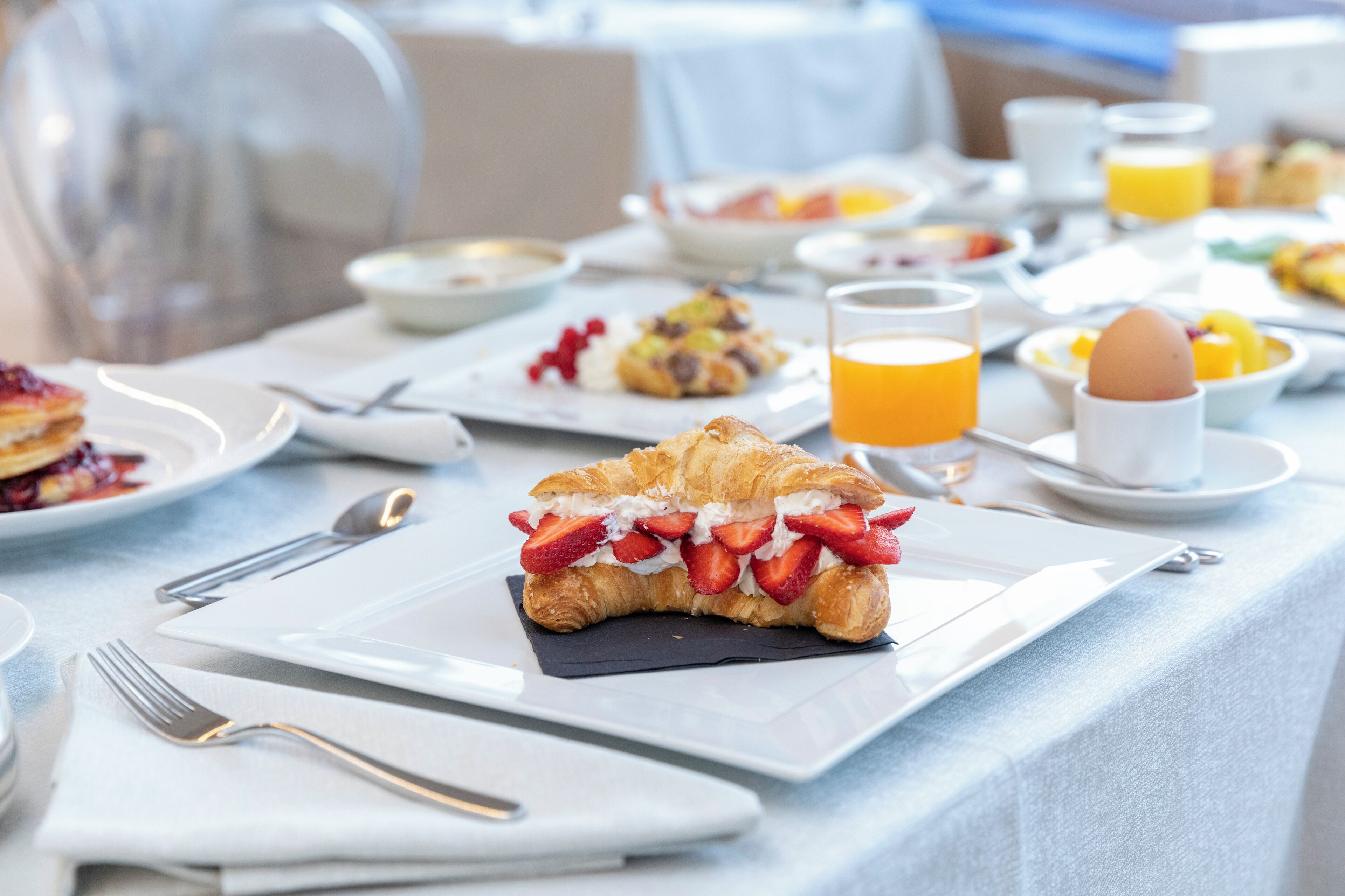 Una colazione con croissant, frutta e succo d'arancia su un tavolo.