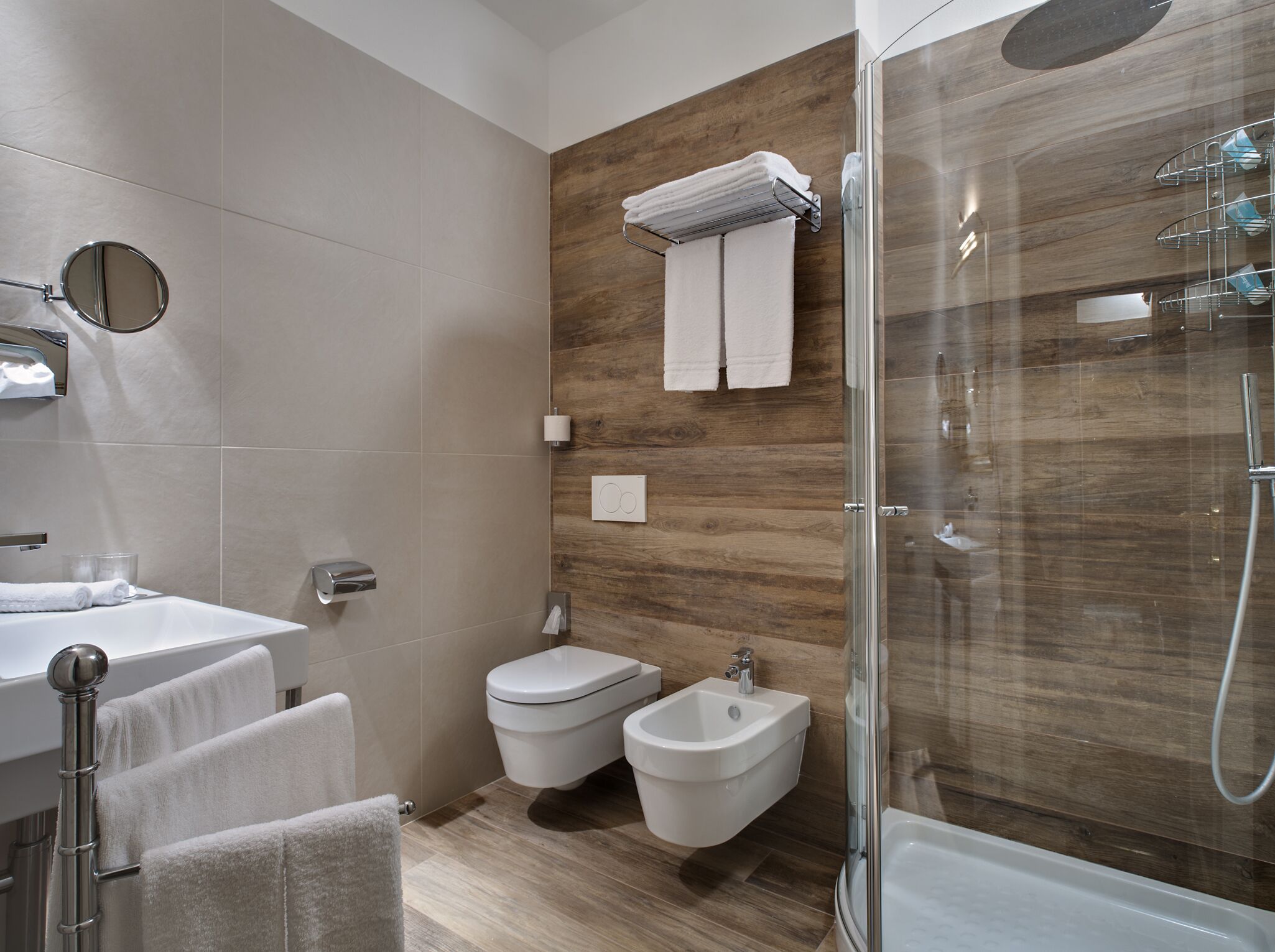 Een moderne badkamer met een douche, toilet en bidet.