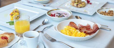 Una mesa de desayuno con diversos platos, incluyendo huevos revueltos, tocino y pasteles.