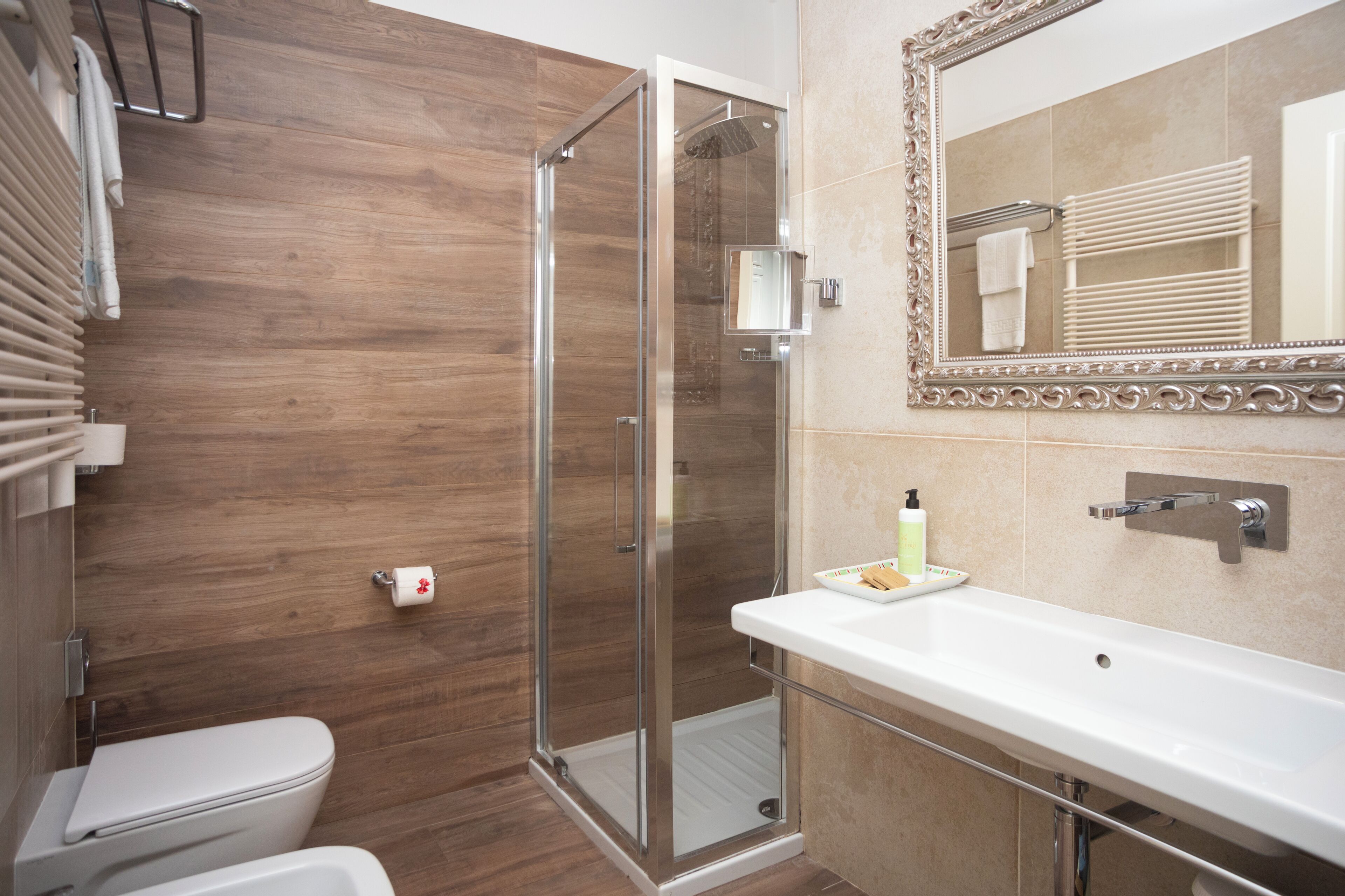 Un baño moderno con ducha envuelta en cristal, un lavabo blanco y un espejo grande.