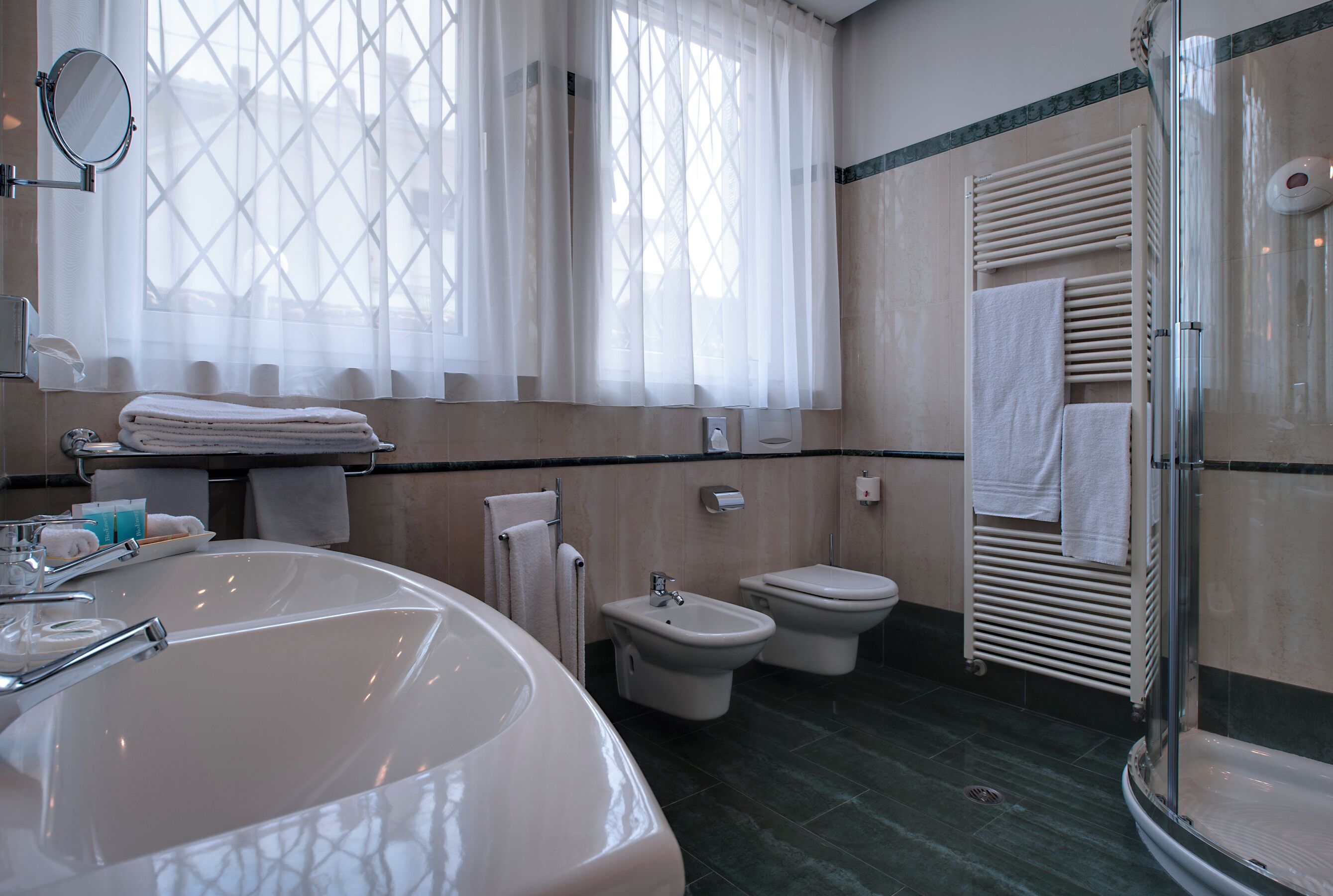 A bathroom with a large sink, bidet, toilet, and a glass shower enclosure.